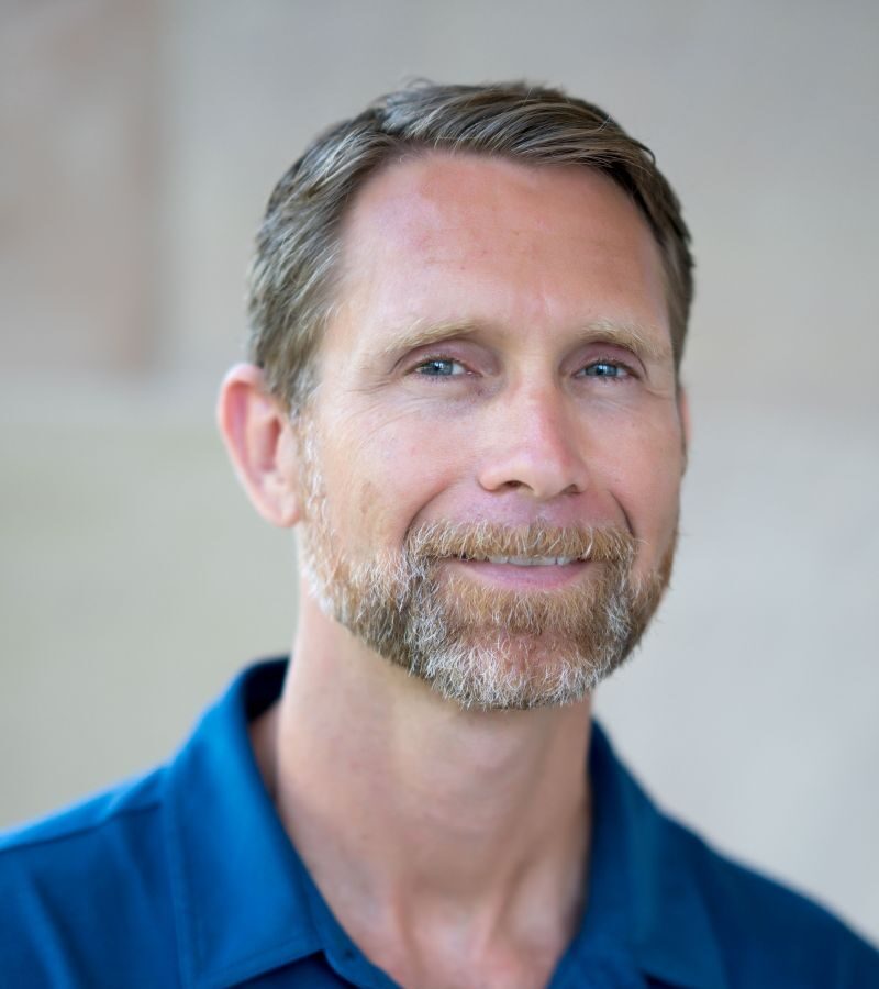 A headshot of Jason Weir wearing a blue polo shirt